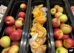 FILE - Apples and orange slices rest in trays for student lunch at the Albert D. Lawton Intermediate School, in Essex Junction, Vt., Thursday, June 9, 2022. (AP Photo/Lisa Rathke)
