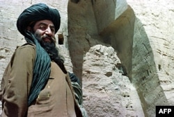 FILE - An unidentified official of the Afghan Taliban militia stands near the virtually destroyed tallest standing Buddha statue in Bamiyan city, in the central Afghanistan, March 26, 2001.