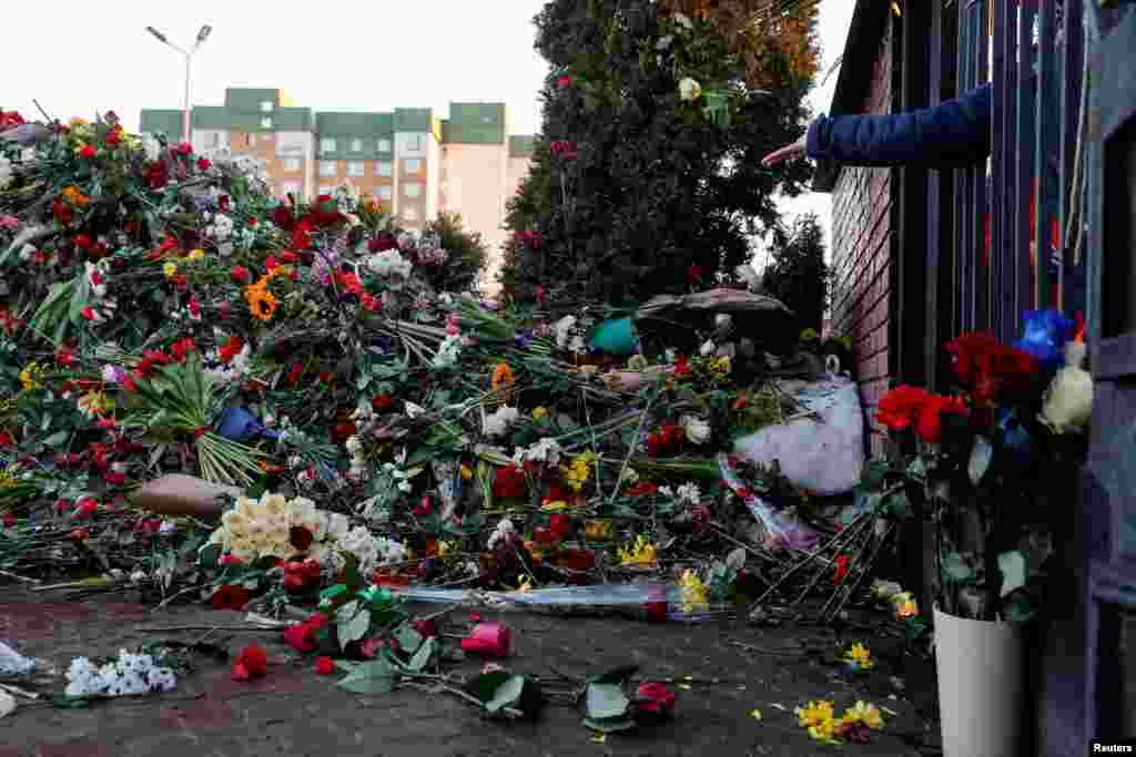 A person throws flowers towards the grave of Russian opposition politician Alexei Navalny while standing in front of a closed entrance to the Borisovskoye cemetery, in Moscow, March 3, 2024.