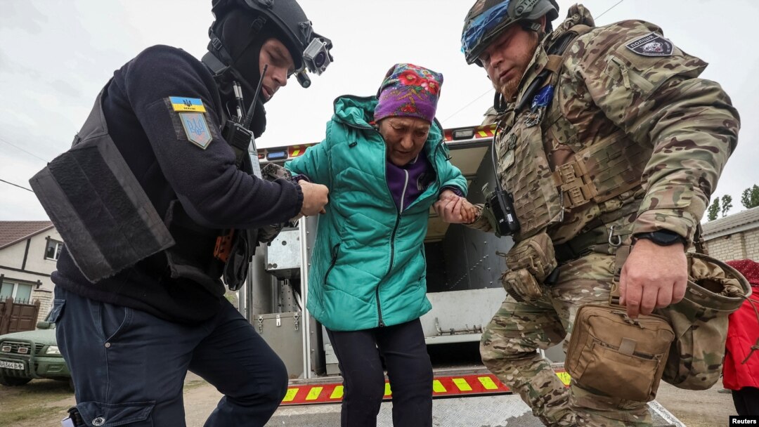 A police officer and a volunteer help a Vovchansk resident evacuate to Kharkiv due to Russian military strikes near the town of Vovchansk in the Kharkiv region, Ukraine, May 17 , 2024.