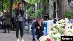 FILE - People react as they pay tribute the day after a school mass shooting when a boy opened fire, killing fellow students and staff in Belgrade, Serbia, May 4, 2023. 