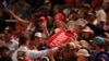 People reach for signs being handed out on the day Republican presidential nominee and former U.S. President Donald Trump holds a campaign rally in Bozeman, Montana, Aug. 9, 2024.