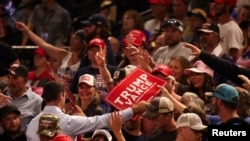 People reach for signs being handed out on the day Republican presidential nominee and former U.S. President Donald Trump holds a campaign rally in Bozeman, Montana, Aug. 9, 2024.