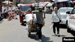 A worker pulls a cart loaded with goods at the Shorja wholesale market, amid high temperatures in Baghdad, Aug. 8, 2023. 