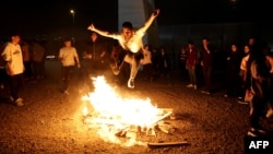 An Iranian jumps over a bonfire during the Wednesday Fire feast, or Chaharshanbeh Soori, held annually on the last Wednesday eve before the Spring holiday of Nowruz, in Tehran on March 14, 2023 ahead of the Nowruz New Year festival.