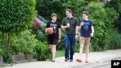 Chicago School Board candidate, former principal Adam Parrott-Sheffer, center, returns home with his sons, Nicholas, 12, left, and Nathan, 14, after treating themselves to ice cream in the Hyde Park neighborhood of Chicago, May 21, 2024.