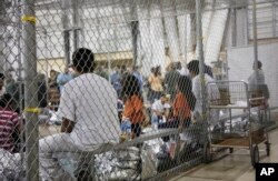 FILE - In this photo provided by US Customs and Border Protection, people who've been taken into custody related to cases of illegal entry into the US, sit in one of the cages at a facility in McAllen, Texas, on June 17, 2018.
