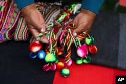 An Aymara Indigenous woman shows handwoven woolen crafts made on the sidelines of a fashion show showcasing Indigenous creations in Iquique, Chile, on July 29, 2023. The Agricultural Development Institute of Chile organized the show to boost camelid farming and craft sales.