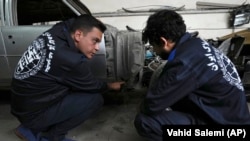 Khosro Dahaghin, left, talks with a worker at his workshop while restoring a Cadillac Seville, in Roudehen, some 30 miles (45 kilometers) east of downtown Tehran, Iran, Wednesday, June 7, 2023. (AP Photo/Vahid Salemi)
