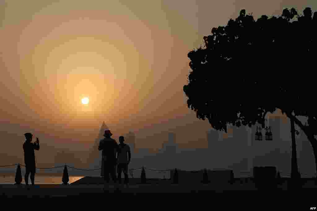 A man snaps a picture at the West Bay district in Doha, Qatar, on a hot and humid summer day.