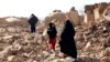 (FILE) A woman with her children walk amid debris after a powerful earthquake in Afghanistan.