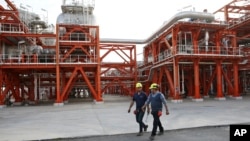 FILE - Two Iranian technicians walk at a natural gas refinery at the South Pars gas field on the northern coast of the Persian Gulf, in Asaluyeh, Iran, March 16, 2019.