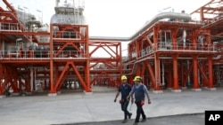 FILE - Two Iranian technicians walk at a natural gas refinery at the South Pars gas field on the northern coast of the Persian Gulf, in Asaluyeh, Iran, March 16, 2019.