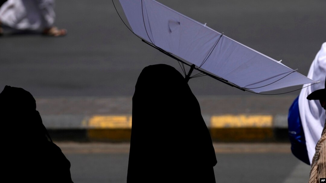A woman holds an umbrella to protect herself from the sun as she leaves after offering prayers outside at the Grand Mosque, during during the annual Hajj pilgrimage in Mecca, Saudi Arabia, June 13, 2024.