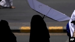 A woman holds an umbrella to protect herself from the sun as she leaves after offering prayers outside at the Grand Mosque, during during the annual Hajj pilgrimage in Mecca, Saudi Arabia, June 13, 2024.