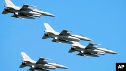 FILE - U.S. made F-16 fighter jets fly in the sky over Poland's capital as they take part in a massive military parade to celebrate the Polish Army Day, in Warsaw, Poland, Aug. 15, 2023.