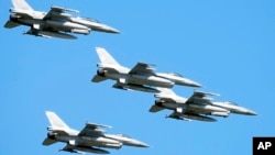 FILE - U.S. made F-16 fighter jets fly in the sky over Poland's capital as they take part in a massive military parade to celebrate the Polish Army Day, in Warsaw, Poland, Aug. 15, 2023.