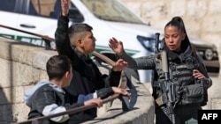 Pripadnica izraelskih snaga sigurnosti s palestinskim dječacima tokom molitve u petak u podne u istočnoj jerusalimskoj četvrti Ras al-Amud, 19. januara 2024. godine, pošto su uvedena starosna ograničenja za pristup kompleksu džamije Al-Aqsa.