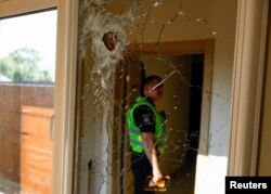 A police officer is reflected in a mirror on a wall of residential house damaged by part of a missile during Russian missile and drone strikes, amid Russia's attack on Ukraine, in Kyiv, Ukraine.