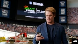FILE - Fox Sports broadcaster Greg Olsen retrieves his receipt after placing the first ceremonial bet in North Carolina during a DraftKings event celebrating the launch of mobile and online sports wagering, March 11, 2024, in Charlotte, N.C.