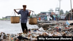 FILE - Seorang lelaki berjalan melewati tumpukan sampah di sebuah pantai di perkampungan nelayan Teluk Pandeglang, Banten, 15 Maret 2024. (Willy Kurniawan/REUTERS)