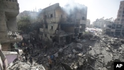 FILE - Palestinians look at the aftermath of the Israeli bombing in Nuseirat refugee camp, Gaza Strip, on June 8, 2024. The U.N. human rights office is citing possible war crimes by Israeli forces and Hamas in connection with a raid that freed four hostages over the weekend. 