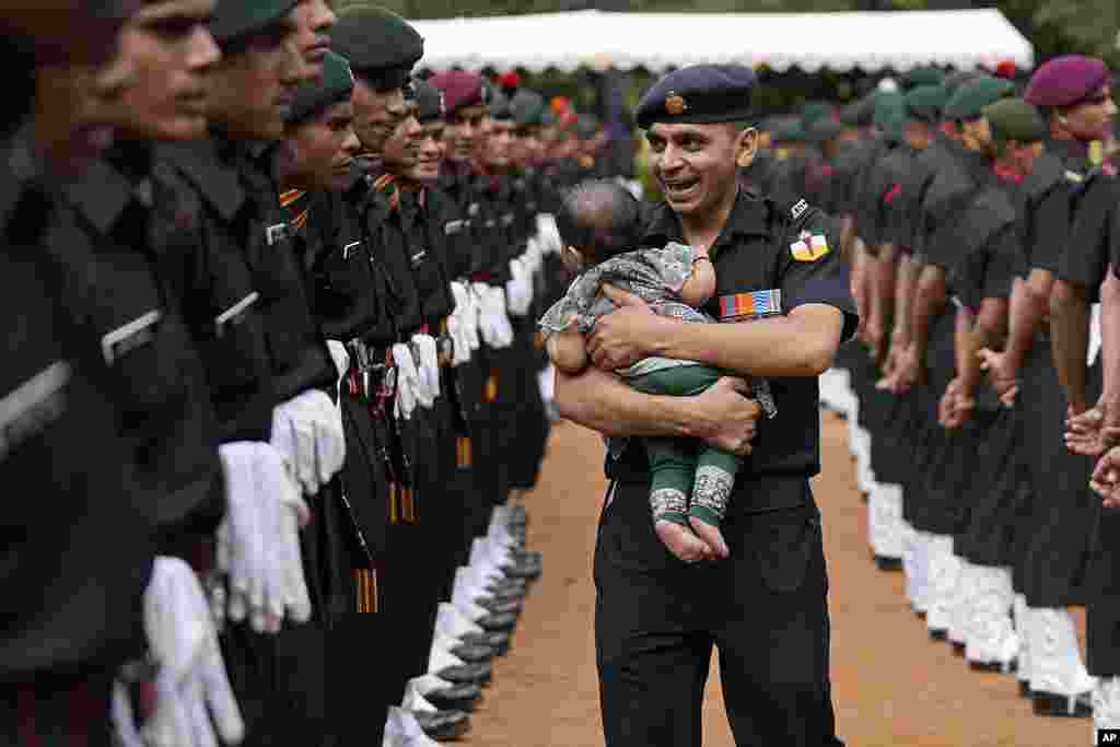 An Indian Army soldier carrying his baby reacts as he walks past graduating soldiers from the first batch of Agniveer scheme during their graduation ceremony in Bengaluru, India.&nbsp;Agniveer, a new short-term job program announced by the government for the military, was launched in June 2022.&nbsp;