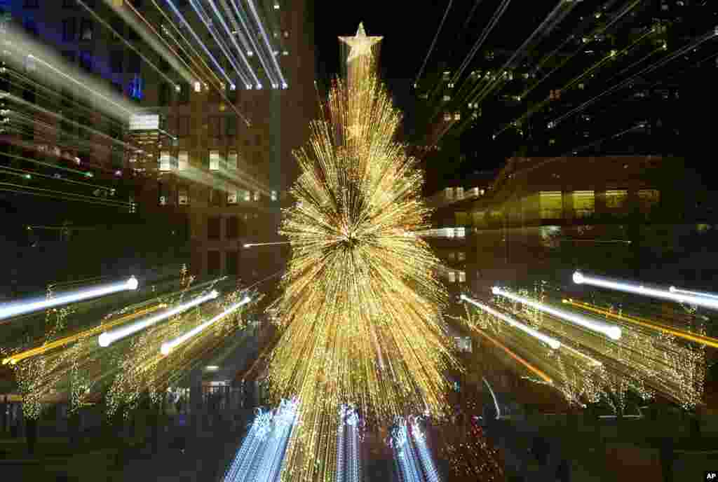 Tourists walk past the Millennium Park Christmas tree in a timed exposure with a zoom lens, Dec. 11, 2023, in Chicago, Illinois.