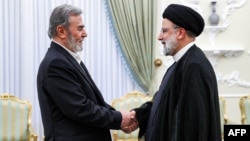 This handout picture provided by the Iranian presidency on shows Iran's President Ebrahim Raisi, right, receiving Ziad al-Nakhalah, secretary-general of the Palestinian Islamic Jihad movement, in Tehran on June 19, 2023. (Photo by Iranian Presidency/AFP) 