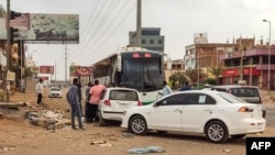 People prepare to board a bus departing from Khartoum in the Sudanese capital's south on April 24, 2023, as battles rage in the city between the army and paramilitaries.