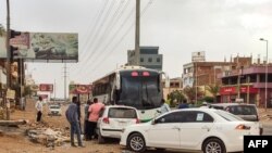 People prepare to board a bus departing from Khartoum in the capital's south on April 24, 2023, as battles rage in the city between the army and paramilitaries.