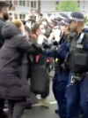 In this photo taken from video, British police officers push back protesters who were trying to stop the transfer of asylum seekers from a hotel in southeast London to a barge off southern England.