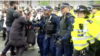 In this photo taken from video, British police officers push back protesters who were trying to stop the transfer of asylum seekers from a hotel in southeast London to a barge off southern England.