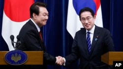 FILE - South Korean President Yoon Suk Yeol, left, and Japanese Prime Minister Fumio Kishida, right, shake hands following a joint news conference at the prime minister's office in Tokyo, Japan, March 16, 2023.