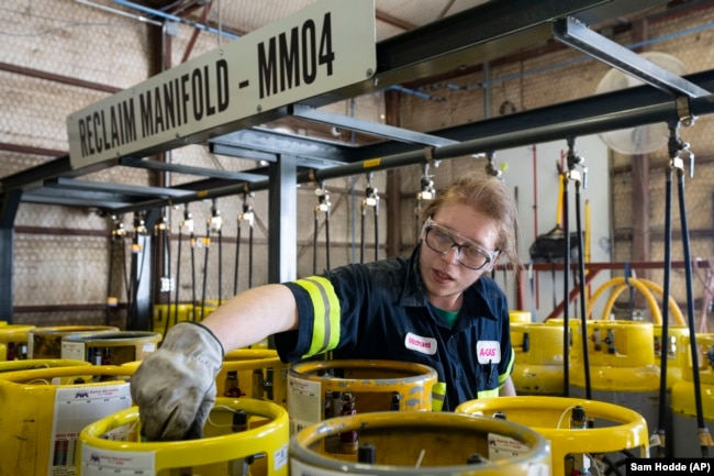 An operator prepares used cylinders to be drained of remaining refrigerant at the A-Gas Rhome facility on Monday, Oct. 9, 2023, in Rhome, Texas. (AP Photo/Sam Hodde)