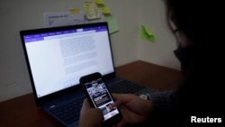 Xenia Oliva, reportera de investigación de Gato Encerrado, a quien le piratearon el teléfono siete veces, incluida la extracción de datos, revisa su teléfono en la oficina de su medio de prensa en San Salvador, El Salvador, el 11 de enero de 2022.