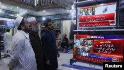 Men watch television screens as they await the appearance of Pakistan's jailed former Prime Minister Imran Khan, expected to be streamed live during a video proceeding of the Supreme Court of Pakistan, at a market in Peshawar, Pakistan May 16, 2024.