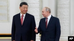 FILE - Russian President Vladimir Putin, right, speaks to Chinese President Xi Jinping as they attend an official welcome ceremony at The Grand Kremlin Palace, in Moscow, March 21, 2023.