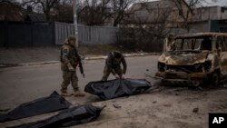 ARHIVA - Ukrajinski vojnici sklanjaju posmrtne ostatke ubijenih civila u Buči, 5. april 2022.(Foto: AP/Felipe Dana)
