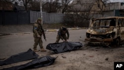 ARHIVA - Ukrajinski vojnici sklanjaju posmrtne ostatke ubijenih civila u Buči, 5. april 2022.(Foto: AP/Felipe Dana)

