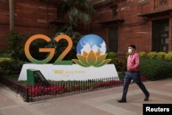 Seorang pria berjalan melewati logo G20 di luar Kementerian Keuangan di New Delhi, India, 1 Maret 2023. (Foto: REUTERS/Anushree Fadnavis)