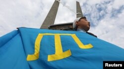 Учасник тримає кримськотатарський прапор під час мітингу, присвяченого річниці масової депортації кримських татар з регіону в 1944 році, в Євпаторії, Крим, 18 травня 2021 року. REUTERS/Alexey Pavlishak