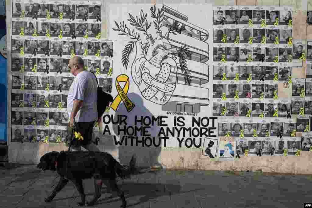 People walk past posters of Israelis held hostage by Palestinian militants in Gaza since October 7, on a street in Tel Aviv, amid the ongoing conflict in the Gaza Strip between Israel and the militant Hamas movement. 