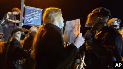 A pro-Palestianian protester holds up a sign as she stands in front of a police officer on the campus of Northern Arizona University, in Flagstaff, Arizona, April 30, 2024.