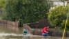Un niño y un hombre andan en bicicleta a través de las inundaciones en Watsonville, California, el sábado 11 de marzo de 2023. (Foto AP/Nic Coury)