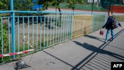 A child walks past debris from a Russian missile strike in Kyiv on May 18, 2023, during the Russian invasion of Ukraine. Ukraine said Russia launched 30 cruise missiles across the country overnight; one breached air defenses, killing one and wounding two.