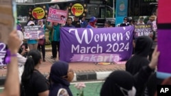 Aktivis membentangkan spanduk saat aksi unjuk rasa Hari Perempuan Internasional di Jakarta, Indonesia, Jumat, 8 Maret 2024. (AP/Dita Alangkara)