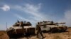 Seorang tentara Israel berjalan di samping tank yang berada di dekat perbatasan Israel-Jalur Gaza, pada 2 Mei 2024. (Foto: Reuters/Amir Cohen)
