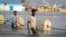 FILE: Men walk through floodwaters on a street in the town of Beledweyne, in Central Somalia on Monday, May 15, 2023.