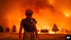 Grant Douglas pauses while evacuating as the Park Fire jumps Highway 36 near Paynes Creek in Tehama County, California, July 26, 2024. The fire is the largest blaze in California this year.